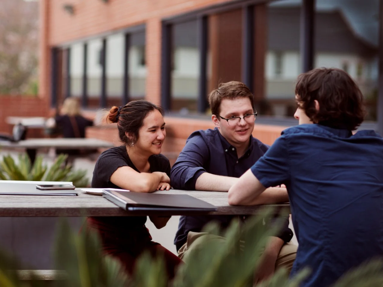 Group of three students sitting outdoors at a table